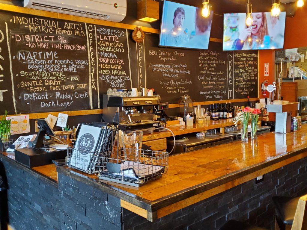 The bar at AJ's Kitchen, with drink selections written on the chalk board, restaurant branding